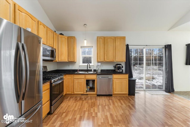 kitchen with lofted ceiling, sink, hanging light fixtures, light hardwood / wood-style flooring, and stainless steel appliances