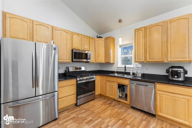 kitchen with appliances with stainless steel finishes, decorative light fixtures, lofted ceiling, sink, and light hardwood / wood-style flooring