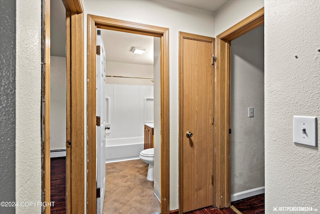 hallway with a baseboard heating unit, baseboards, and a textured wall