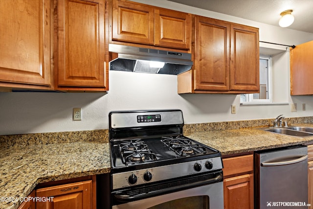 kitchen featuring a sink, brown cabinets, under cabinet range hood, and stainless steel appliances