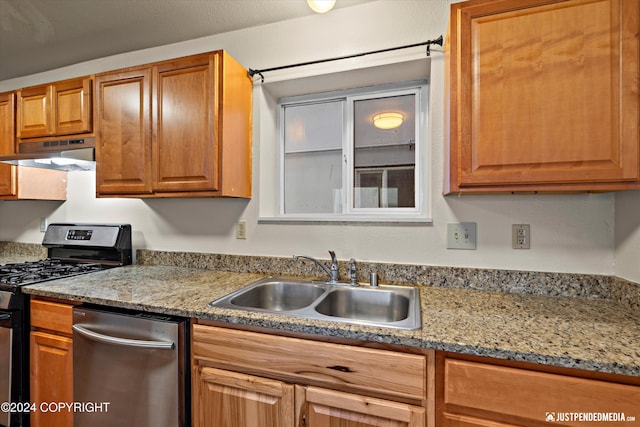 kitchen with brown cabinets, stainless steel appliances, under cabinet range hood, and a sink