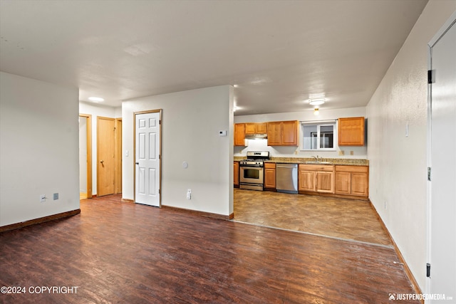 kitchen with dark wood-type flooring, baseboards, light countertops, stainless steel appliances, and a sink