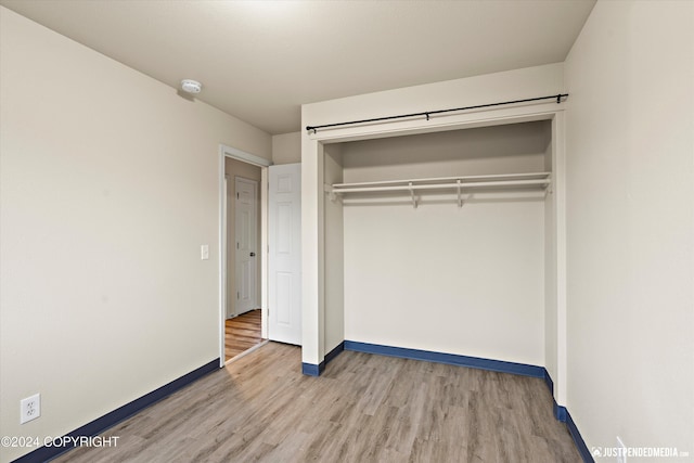 unfurnished bedroom with light wood-style flooring, baseboards, and a closet