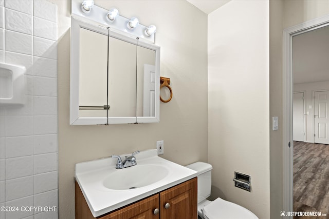 bathroom featuring toilet, wood finished floors, and vanity