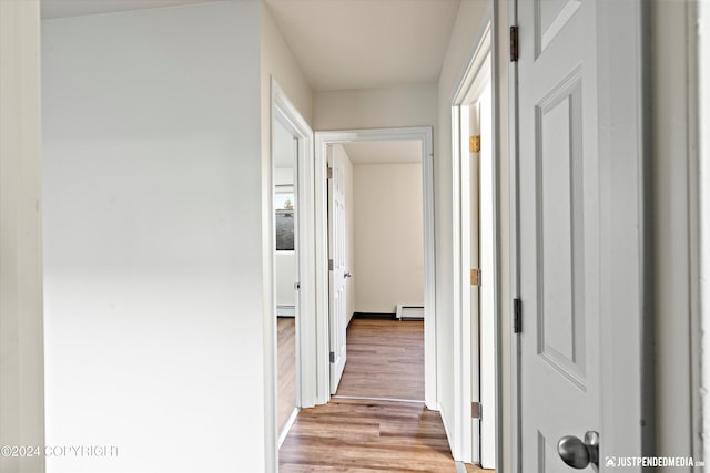 hallway with light wood-type flooring and baseboard heating