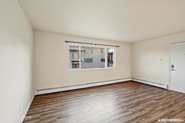 unfurnished room with wood finished floors and a baseboard radiator