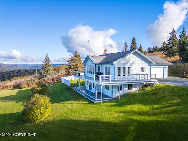 back of property with a deck, a garage, and a yard