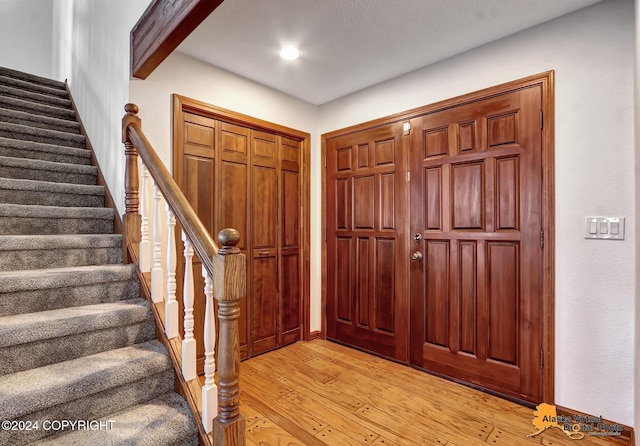 entryway with beamed ceiling and light wood-type flooring