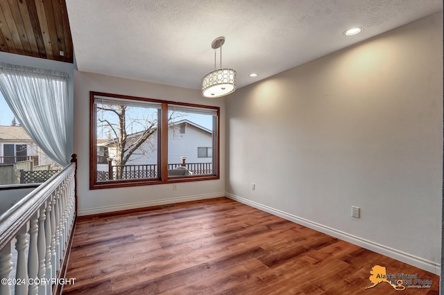 unfurnished dining area featuring a textured ceiling and hardwood / wood-style flooring