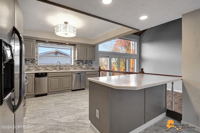 kitchen featuring sink, kitchen peninsula, stainless steel appliances, gray cabinets, and decorative backsplash