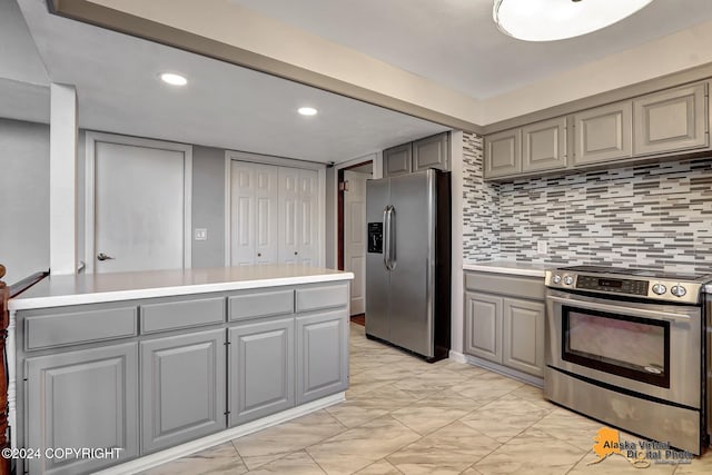 kitchen with gray cabinets, appliances with stainless steel finishes, kitchen peninsula, and backsplash