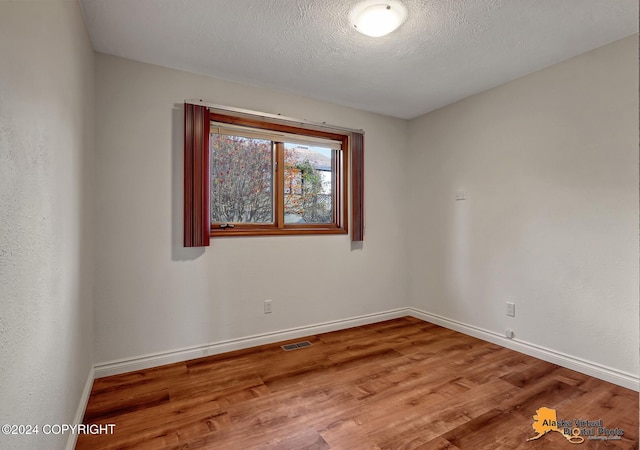 unfurnished room featuring a textured ceiling and wood-type flooring