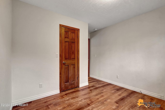 spare room with a textured ceiling and light wood-type flooring