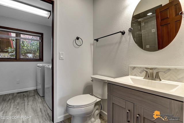 bathroom with decorative backsplash, hardwood / wood-style flooring, toilet, vanity, and washing machine and dryer