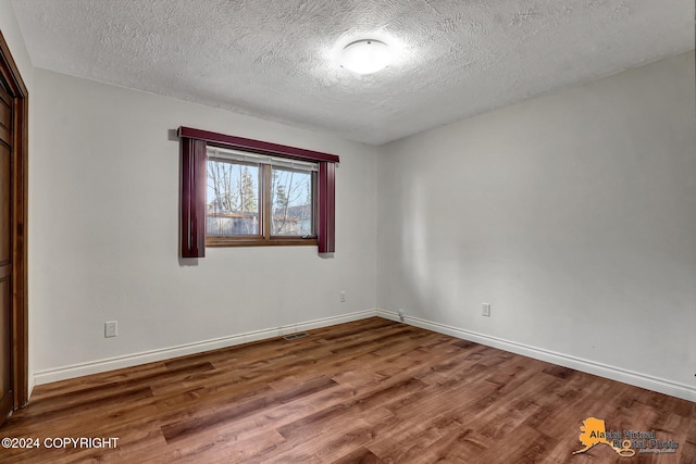 spare room featuring hardwood / wood-style flooring and a textured ceiling