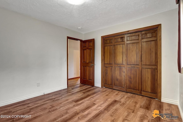 unfurnished bedroom with a closet, a textured ceiling, and light wood-type flooring