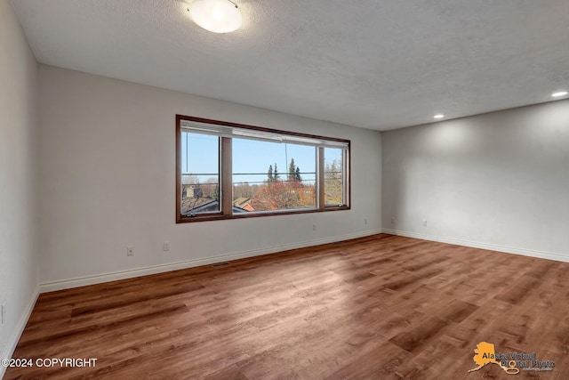 spare room with a textured ceiling and hardwood / wood-style flooring