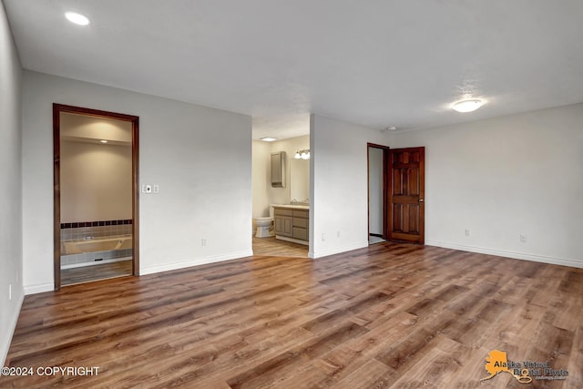 unfurnished bedroom with a notable chandelier, ensuite bath, hardwood / wood-style flooring, and sink