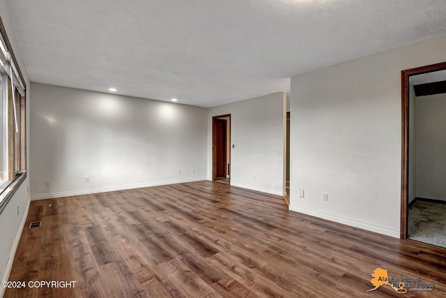 spare room featuring wood-type flooring and a textured ceiling