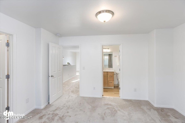 unfurnished bedroom featuring light carpet and ensuite bath