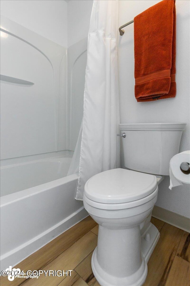 bathroom with toilet, hardwood / wood-style flooring, and shower / bathtub combination with curtain