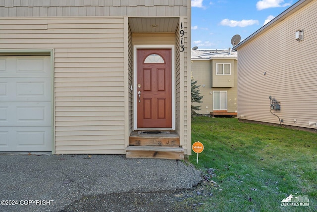 property entrance featuring a lawn and a garage