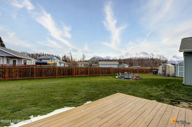 wooden terrace featuring a shed, a lawn, and a mountain view