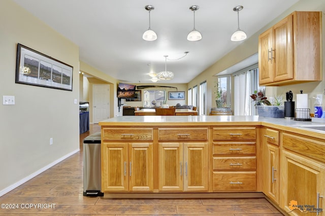 kitchen featuring hanging light fixtures, hardwood / wood-style flooring, a chandelier, and kitchen peninsula