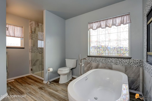 bathroom with toilet, shower with separate bathtub, and hardwood / wood-style flooring