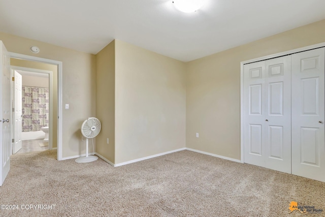 unfurnished bedroom with connected bathroom, light carpet, and a closet