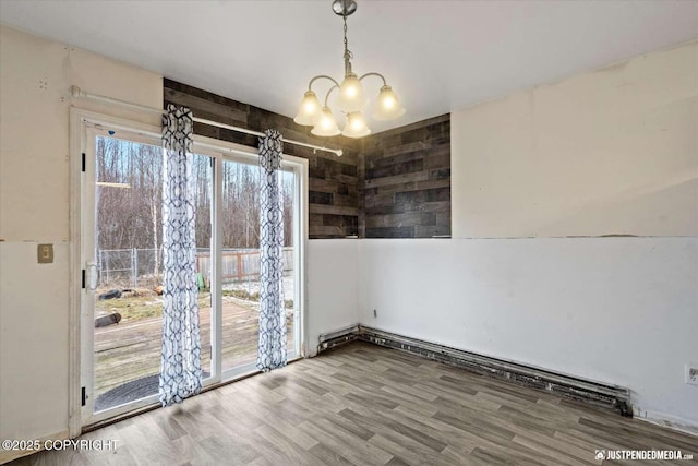 unfurnished dining area with wood-type flooring and an inviting chandelier