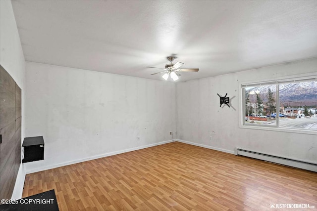 empty room with light hardwood / wood-style flooring, ceiling fan, and baseboard heating