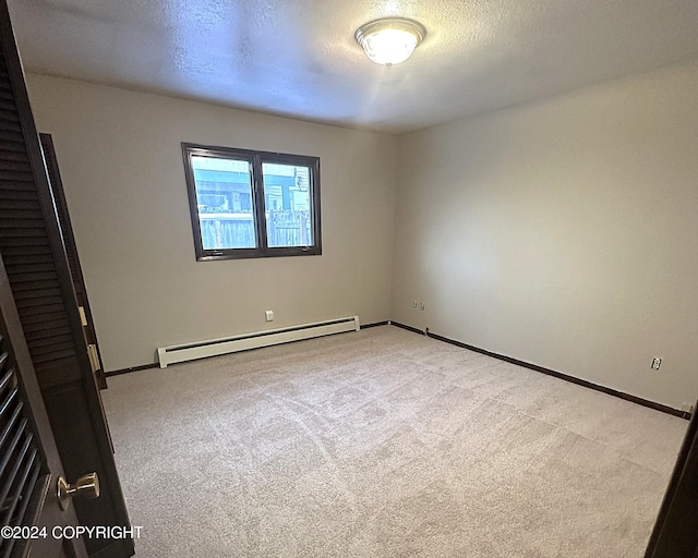 empty room featuring light colored carpet, a textured ceiling, and a baseboard heating unit