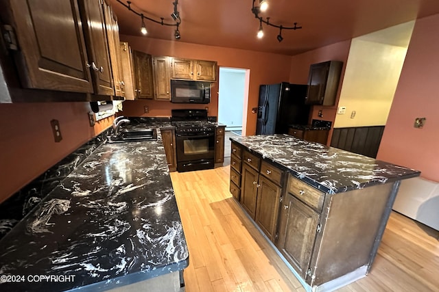 kitchen with rail lighting, sink, black appliances, light hardwood / wood-style flooring, and a center island