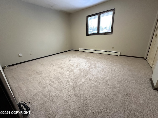 carpeted empty room with a baseboard heating unit