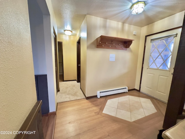 foyer entrance with light hardwood / wood-style flooring, a textured ceiling, and a baseboard heating unit