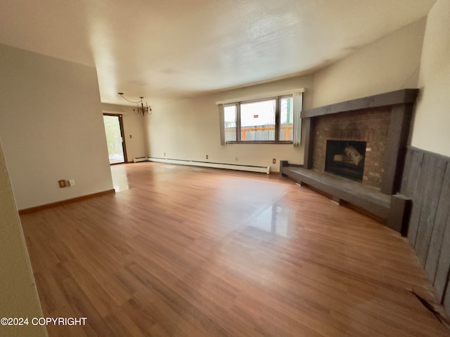 unfurnished living room featuring hardwood / wood-style flooring, an inviting chandelier, and a baseboard radiator