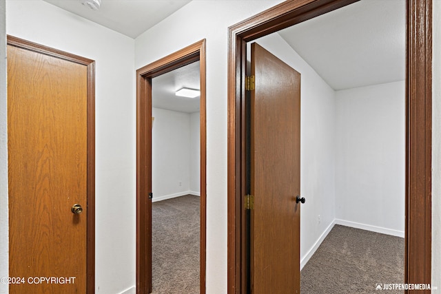 corridor featuring dark colored carpet