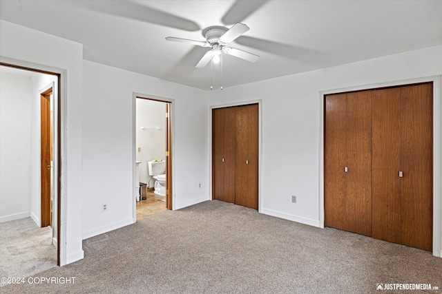 unfurnished bedroom featuring light carpet, two closets, connected bathroom, and ceiling fan