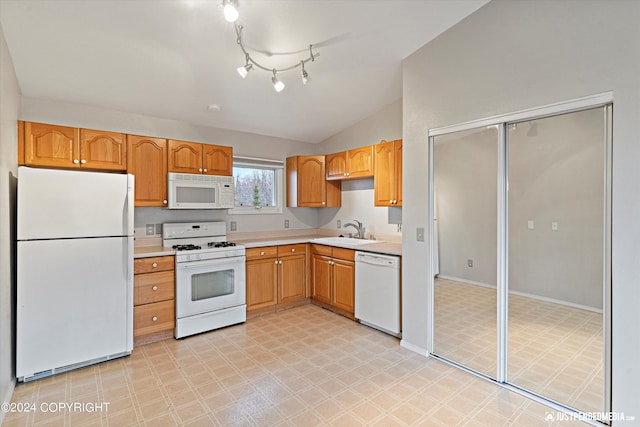 kitchen with vaulted ceiling, white appliances, and sink