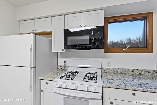 kitchen with light stone countertops, white appliances, and white cabinetry