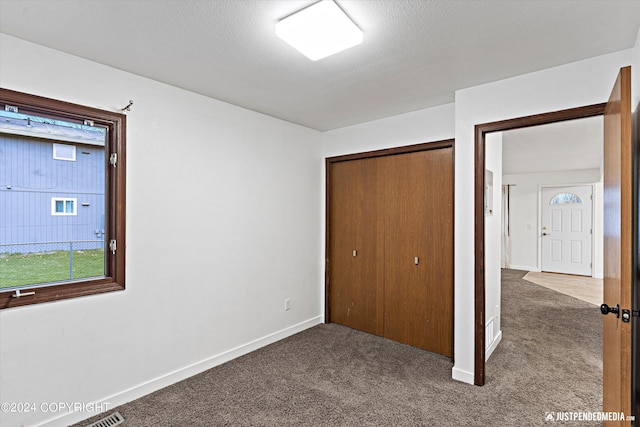 unfurnished bedroom with a closet, carpet, and a textured ceiling