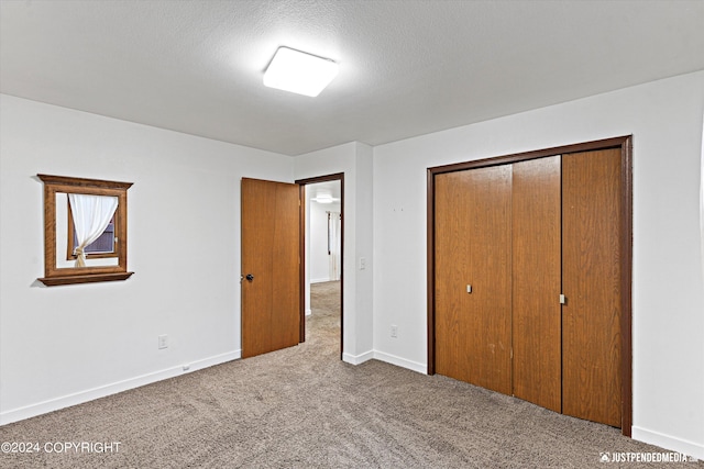 unfurnished bedroom featuring a closet, dark colored carpet, and a textured ceiling