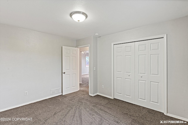 unfurnished bedroom with a closet and dark carpet