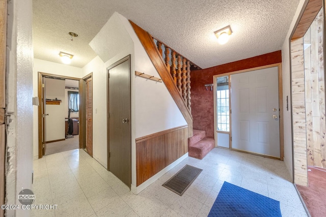 4480 E 138th Ave, Anchorage, AK 99516 - entrance foyer with a textured ceiling, tile patterned floors, stairs, a wainscoted wall, and wood walls