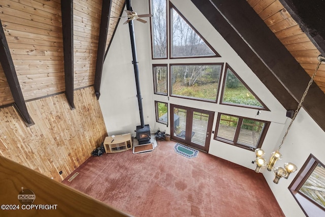 4480 E 138th Ave, Anchorage, AK 99516 - unfurnished living room with high vaulted ceiling, a wood stove, carpet floors, wood ceiling with exposed beams, and wooden walls