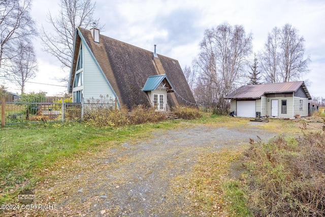 4480 E 138th Ave, Anchorage, AK 99516 - view of property exterior with a garage, an outdoor structure, dirt driveway, french doors, and a chimney