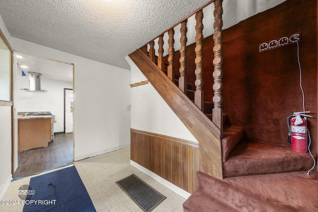 4480 E 138th Ave, Anchorage, AK 99516 - stairs with tile patterned floors, a textured ceiling, wainscoting, and baseboards