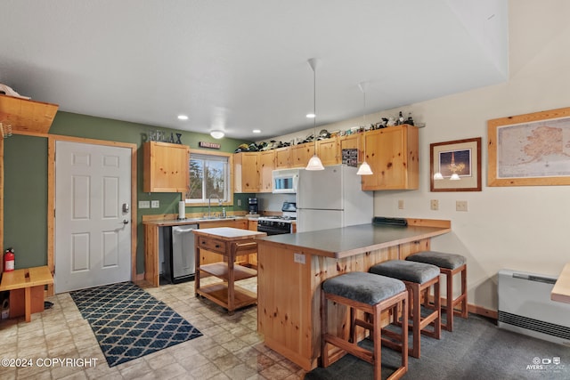 kitchen featuring white appliances, a breakfast bar, light brown cabinets, sink, and kitchen peninsula