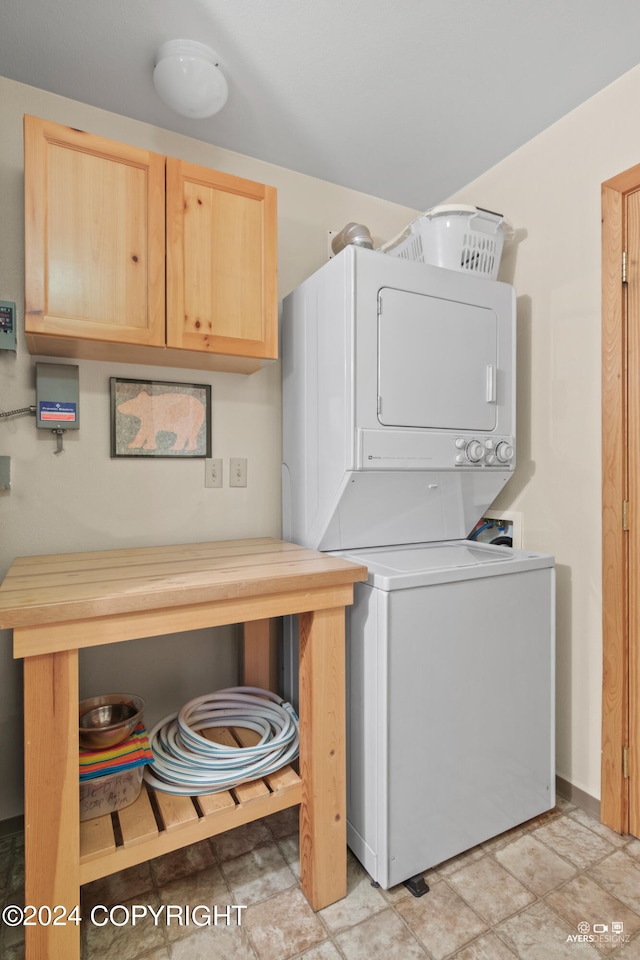 washroom with stacked washer and dryer and cabinets